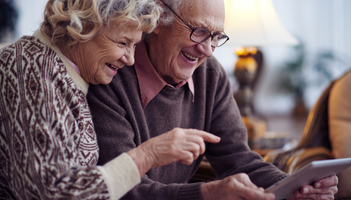 Elder couple looking at their ipad with smile on their face navigating through application process