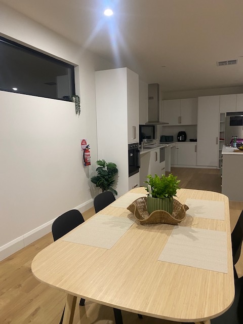 Kitchen and dining in brand-new SDA home in the heart of Morphett Vale, Kenwood Dr, featuring modern open layout and light wood table, part of Australia’s leading disability accommodation provider.