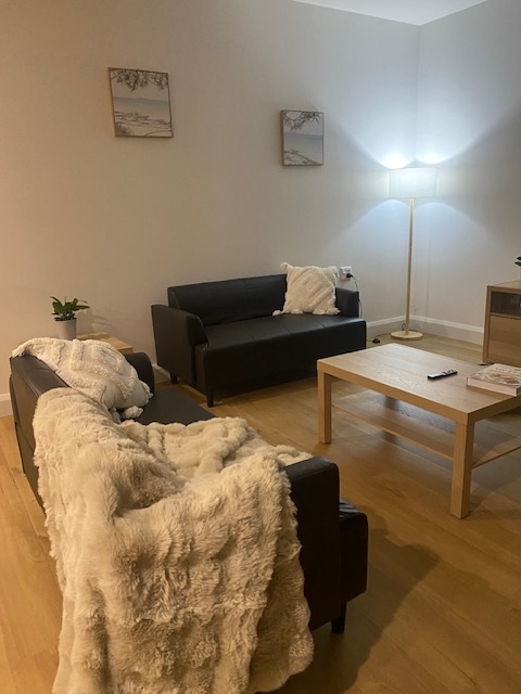 Living area in brand-new SDA home in the heart of Morphett Vale, Kenwood Dr, featuring black sofas, coffee table, and modern decor, part of Australia’s leading disability accommodation provider.