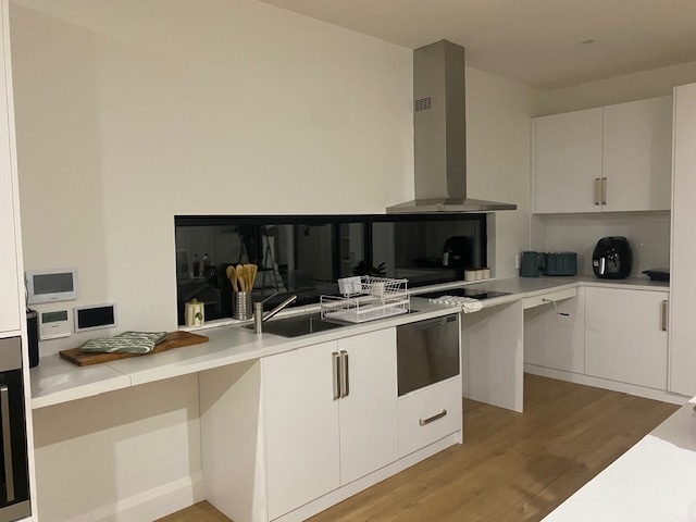 Kitchen in brand-new SDA home in the heart of Morphett Vale, Kenwood Dr, featuring white cabinetry, black splashback, and accessible layout, part of Australia’s leading disability accommodation provider.