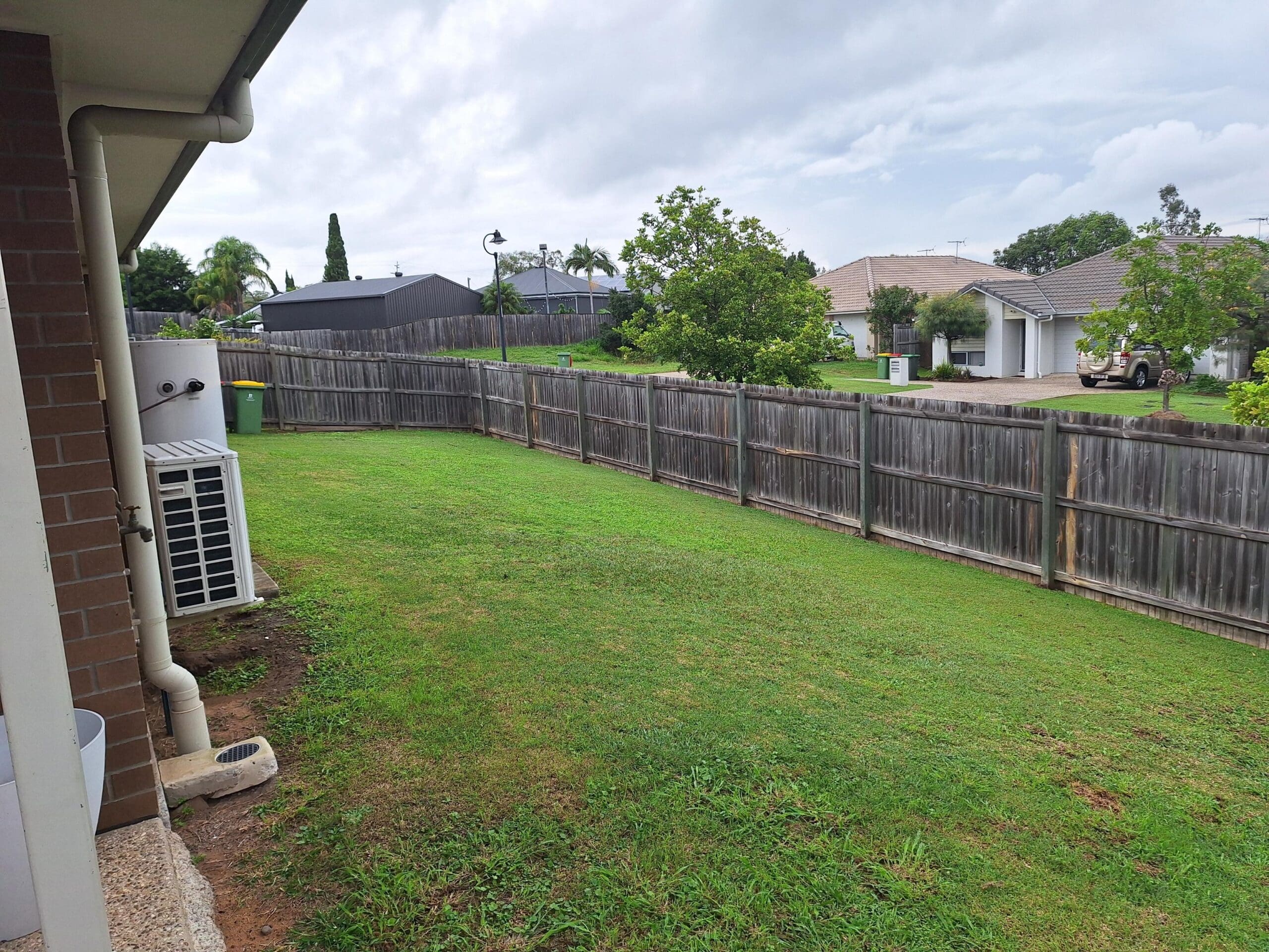 Backyard of welcoming and cosy SIL in Brassall, Ipswich, featuring level lawn, wooden fence, and green space, part of Australia’s leading disability accommodation provider.