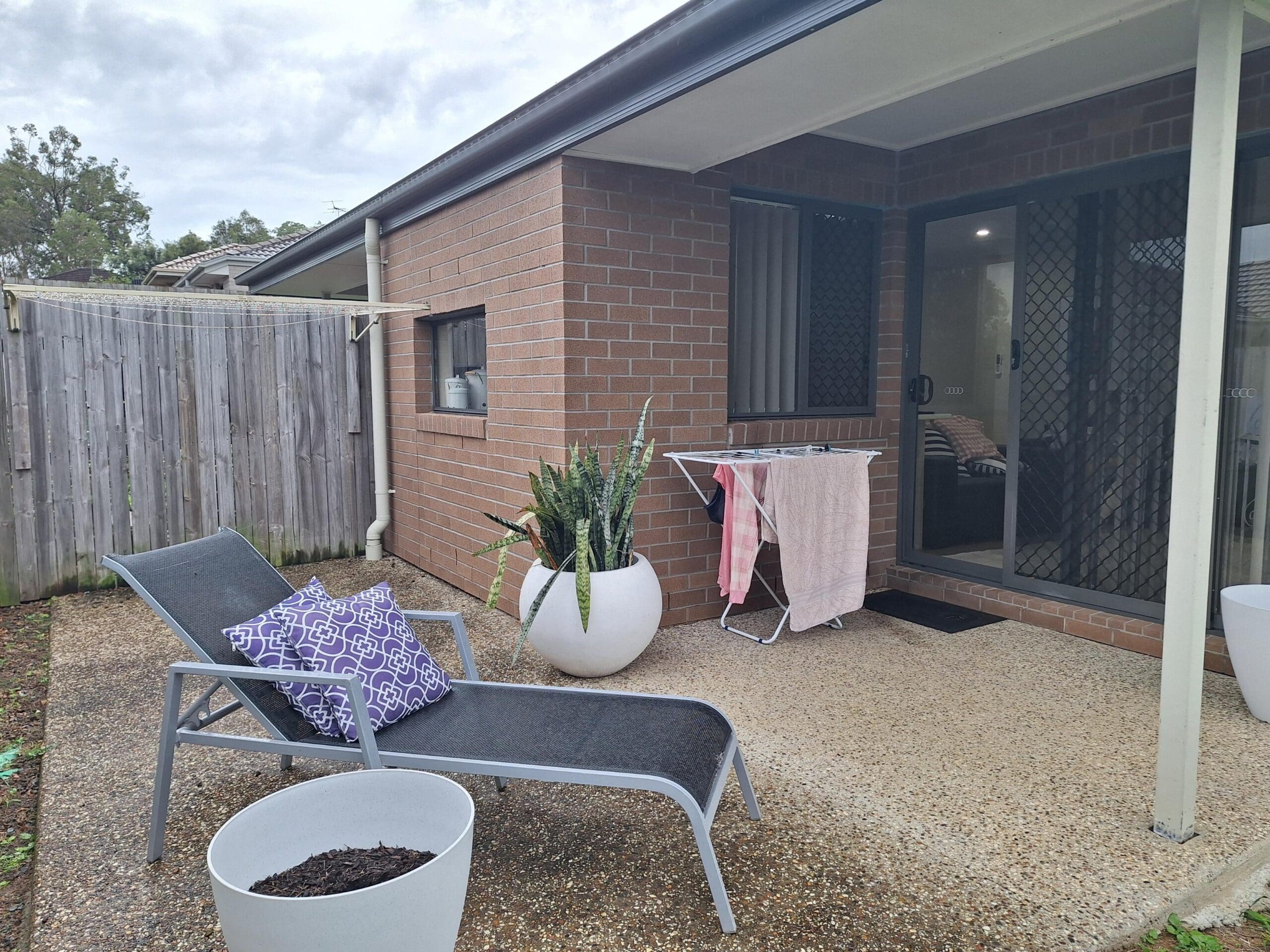 Patio in welcoming and cosy SIL in Brassall, Ipswich, featuring lounge chair, planter, and drying rack, part of Australia’s leading disability accommodation provider.