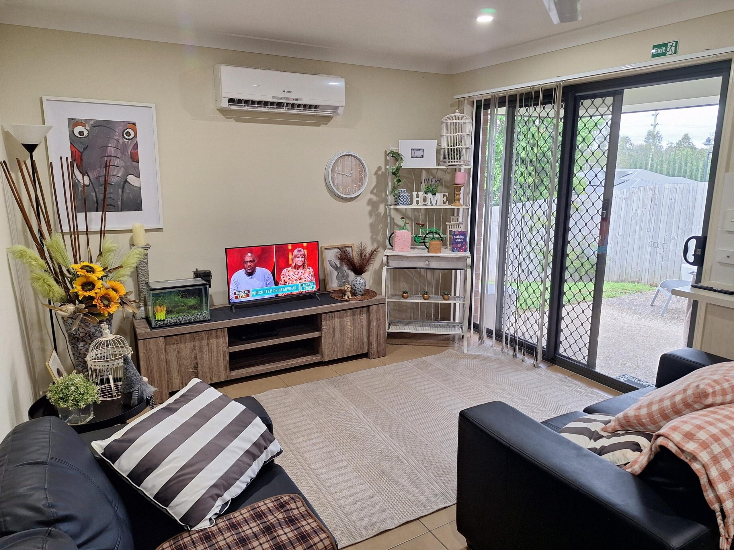 Living room in welcoming and cosy SIL in Brassall, Ipswich, featuring comfortable sofas, TV, and garden view, part of Australia’s leading disability accommodation provider.