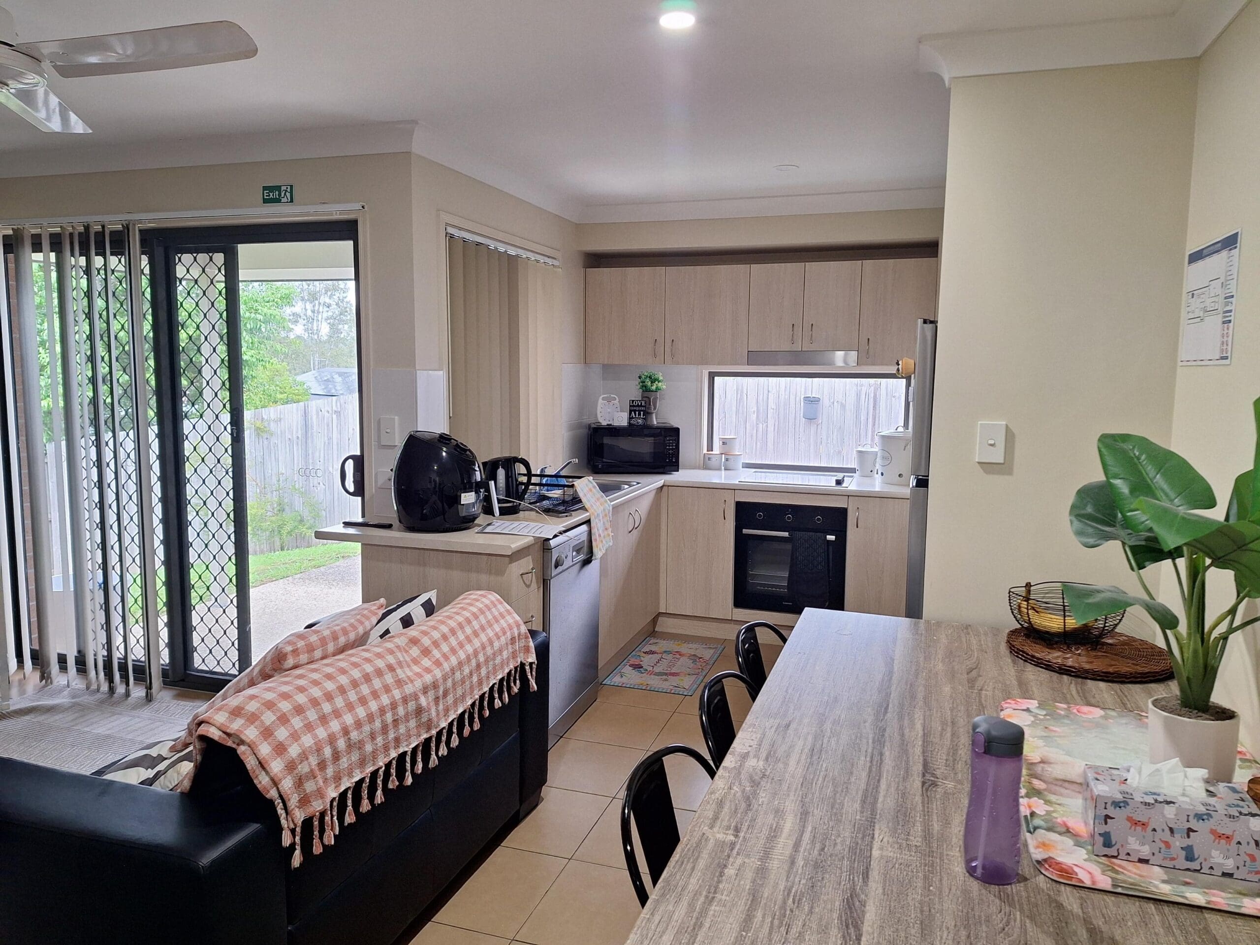 Kitchen in welcoming and cosy SIL in Brassall, Ipswich, open-plan with light wood cabinetry, accessible layout, and natural light, part of Australia’s leading disability accommodation provider