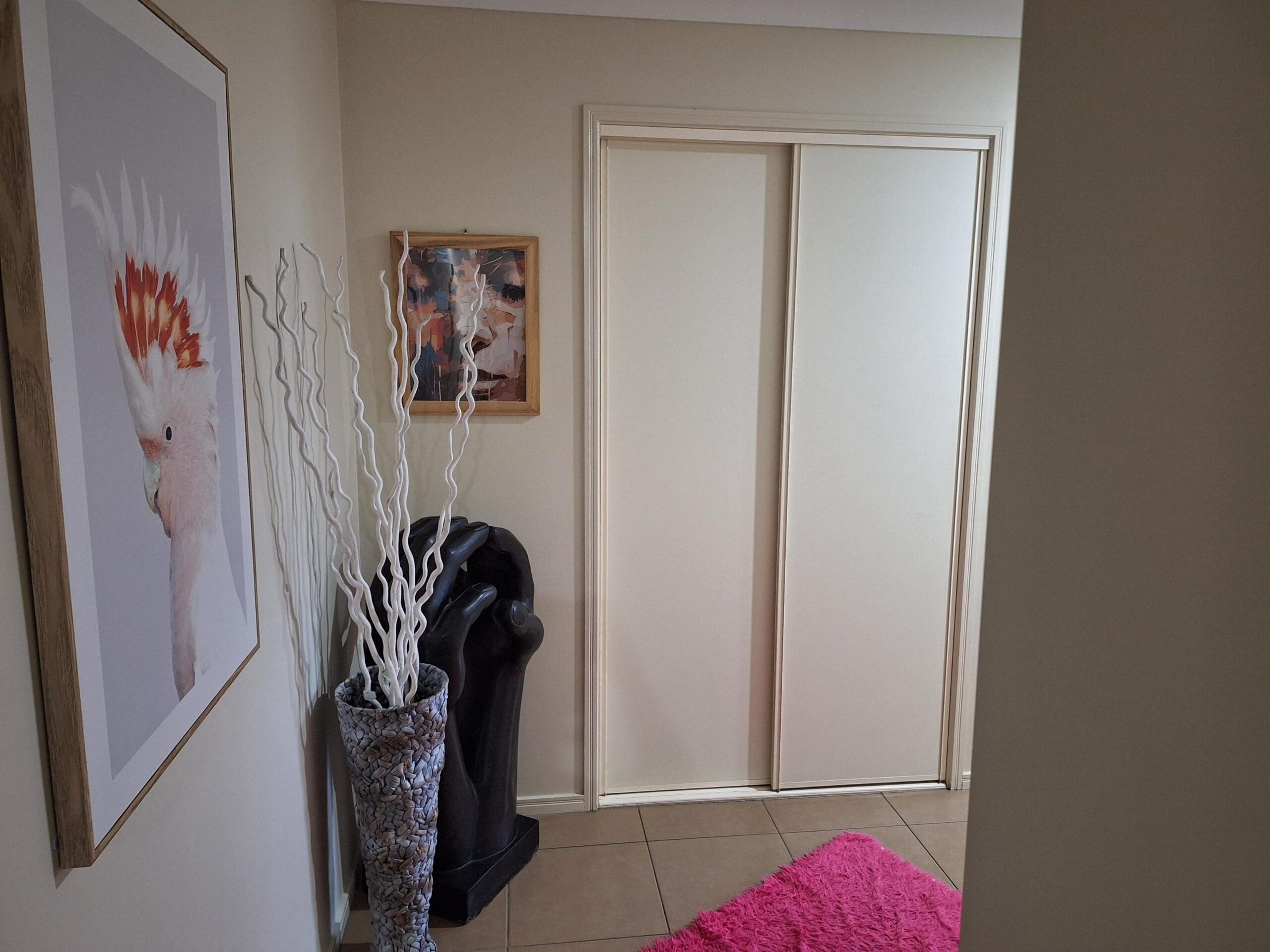 Hallway in welcoming and cosy SIL in Brassall, Ipswich, featuring pink rug, cockatoo art, and decorative elements, part of Australia’s leading disability accommodation provider.