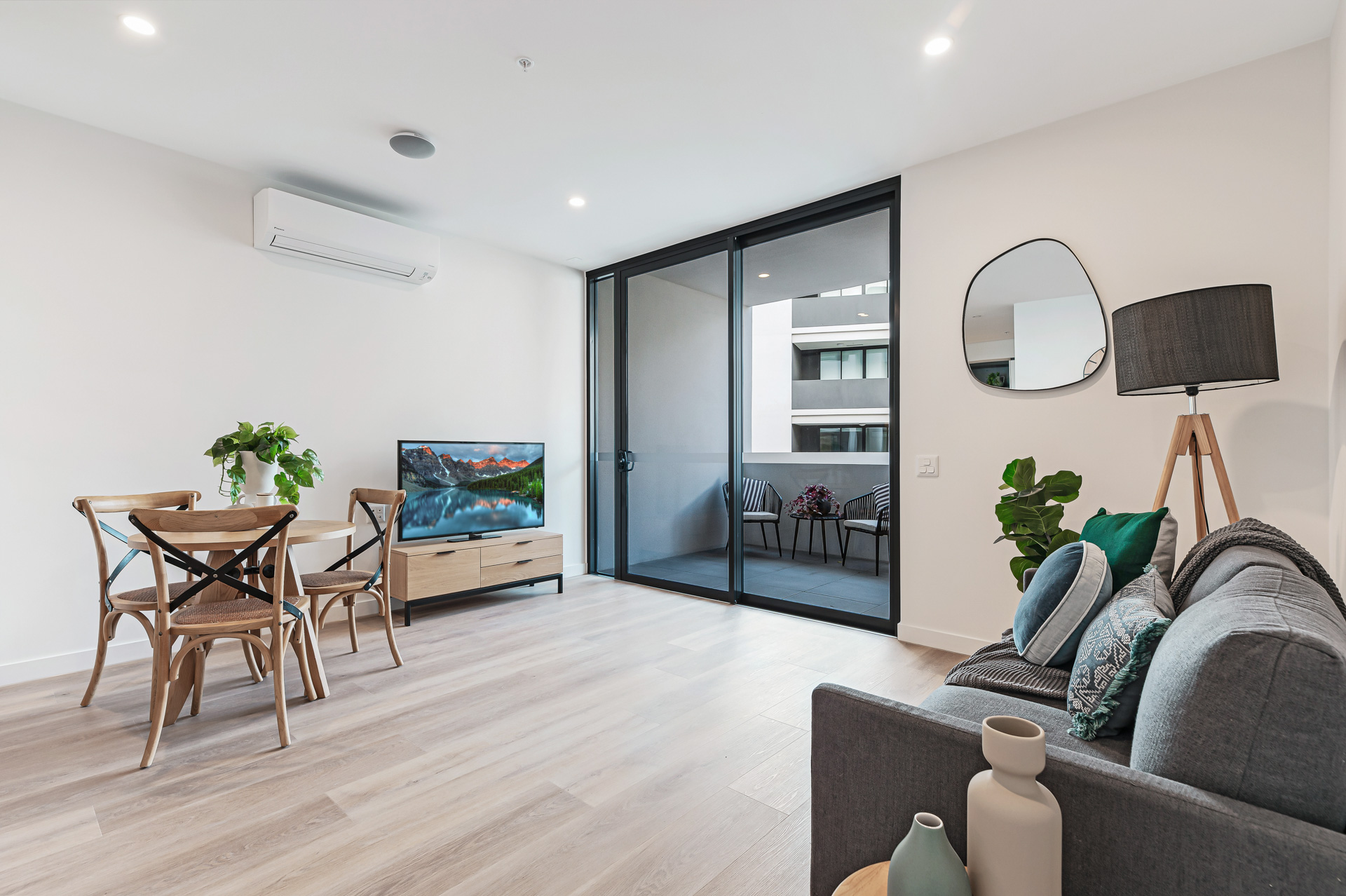 La Scala Avenue living and dining area with sofa, TV, balcony access, air conditioning and timber-look flooring by Australia's leading disability accommodation provider.