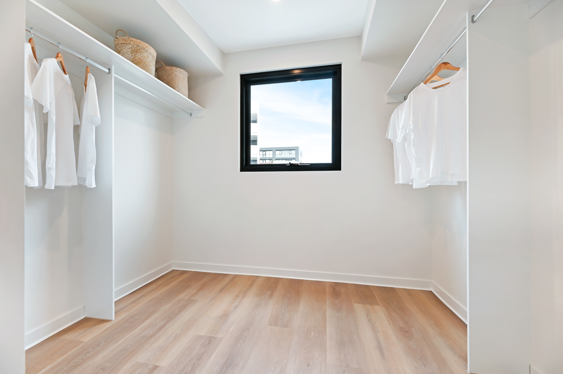 La Scala Avenue walk-in wardrobe with hanging rails, storage shelves, window and timber-look flooring by Australia's leading disability accommodation provider.