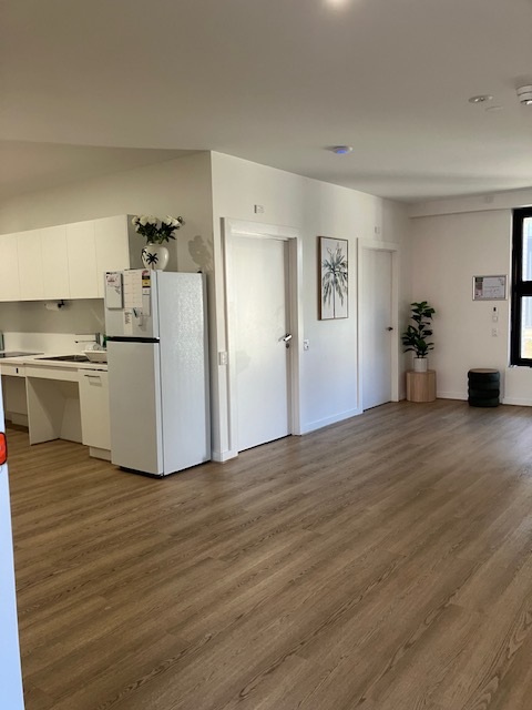 SDA Villa in Fullarton open living area with kitchenette, fridge, timber-look flooring, indoor plant and front entry by Australia's leading disability accommodation provider.