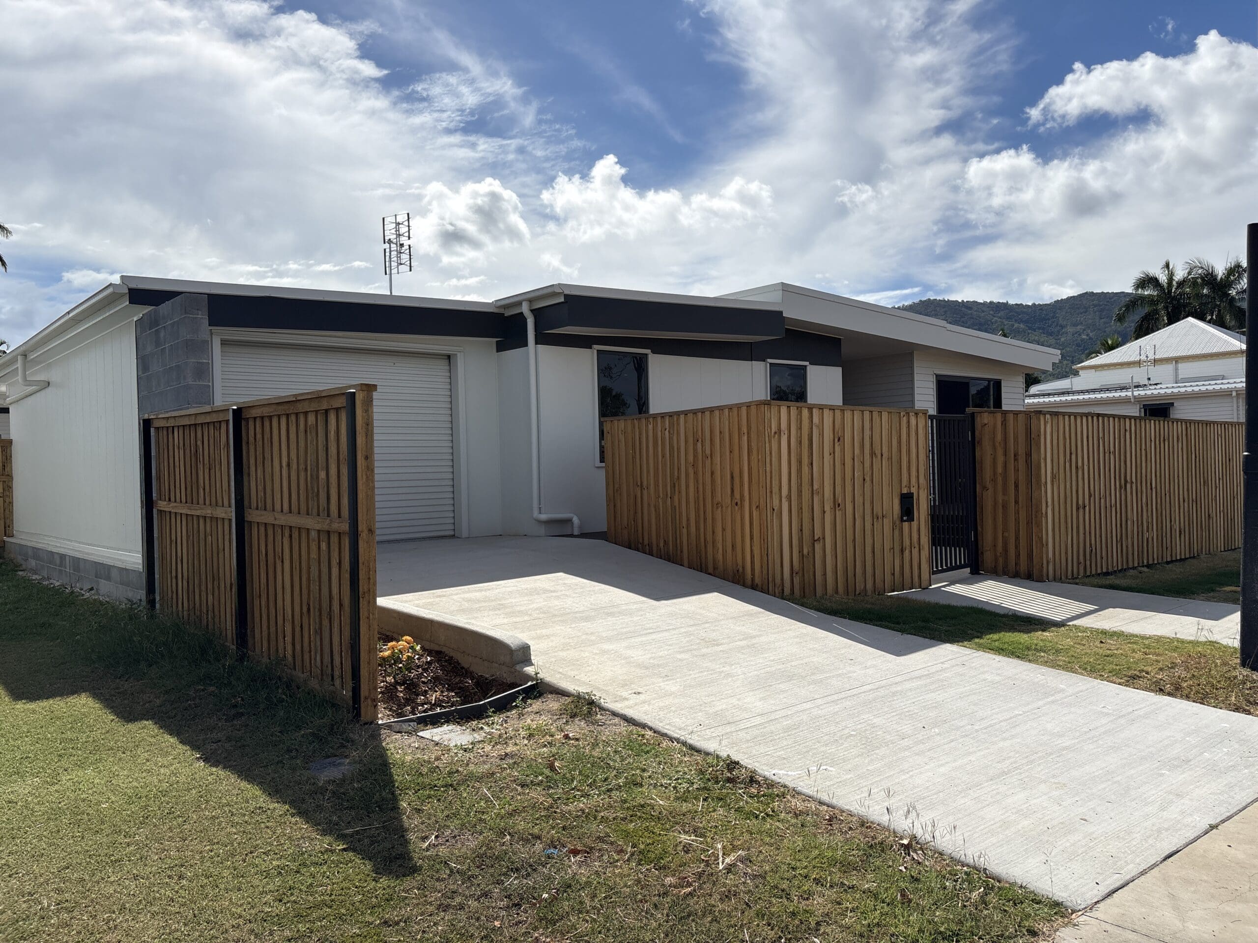 SDA vacancy north of Rockhampton, Kerrigan St Frenchville exterior with garage, concrete driveway, timber fencing and mountain views by Australia's leading disability accommodation provider.