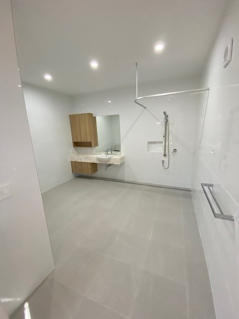 SDA vacancy north of Rockhampton, Kerrigan St Frenchville accessible bathroom with open shower, grab rails, vanity and tiled flooring by Australia's leading disability accommodation provider.