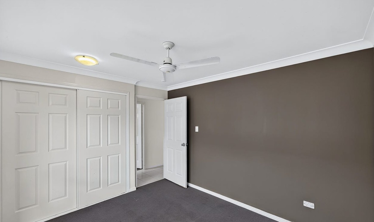 Roomy SIL home in Gracemere, Joseph St Gracemere bedroom with built-in wardrobe, ceiling fan, carpet and feature wall by Australia's leading disability accommodation provider.