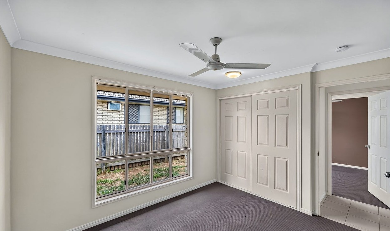 Roomy SIL home in Gracemere, Joseph St Gracemere bedroom with built-in wardrobe, large window, ceiling fan and carpet by Australia's leading disability accommodation provider.